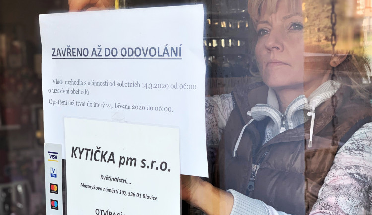 Majitelka květinářství Petra Potřebová vylepuje na dveře provozovny ceduli informující o uzavření obchodu na základě vládního nařízení