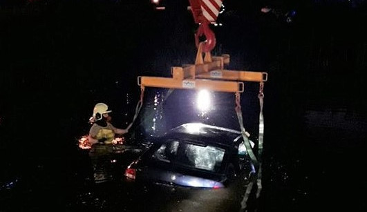 Hasiči vyprošťují auto ze dna rybníka pomocí jeřábu
