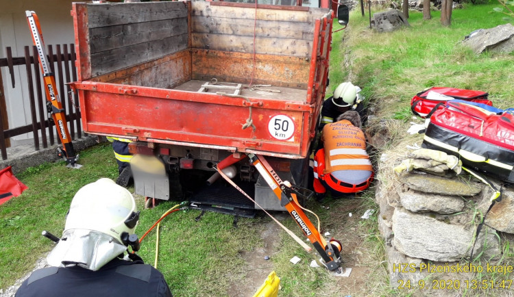 Hasiči a záchranáři vyprošťují muže z pod multikáry