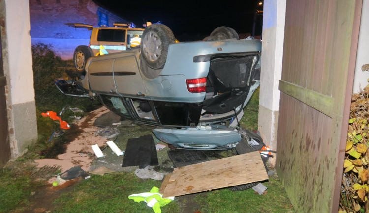 Auto zbořilo hradbu a přistálo na střeše ve vjezdu dalšího domu, řidič od nehody ujel jiným vozem