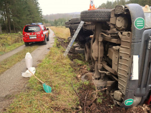 Náklaďák s dřevem skončil převrácený na boku mimo vozovku