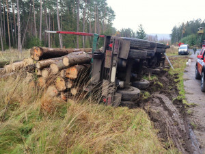 Náklaďák s dřevem skončil převrácený na boku mimo vozovku