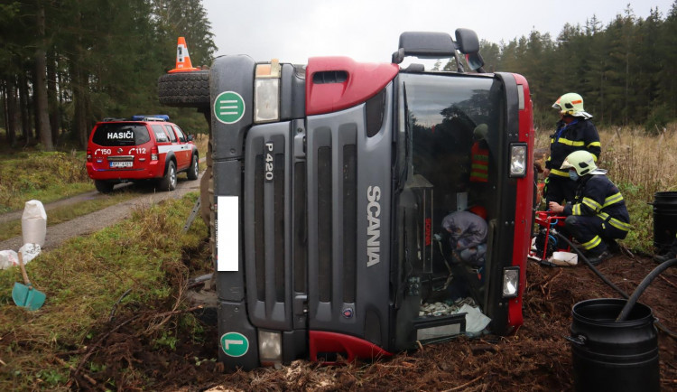 Náklaďák s dřevem skončil převrácený na boku mimo vozovku