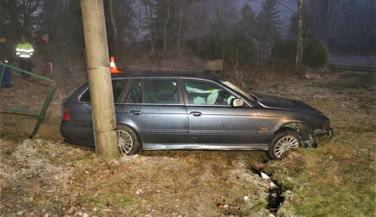 Řidič BMW po smyku na namrzlé silnici smetl dopravní značky i reklamní tabuli
