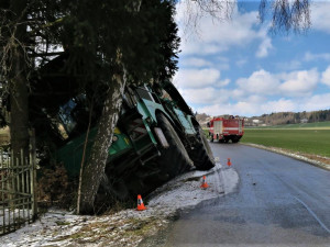 Po smyku na kluzké vozovce ukončil těžký stavební stroj svoji jízdu nárazem do stromů