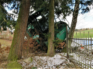 Po smyku na kluzké vozovce ukončil těžký stavební stroj svoji jízdu nárazem do stromů