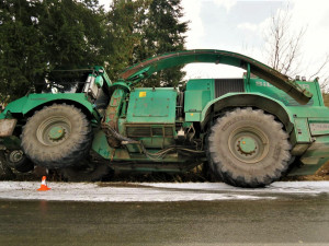 Po smyku na kluzké vozovce ukončil těžký stavební stroj svoji jízdu nárazem do stromů