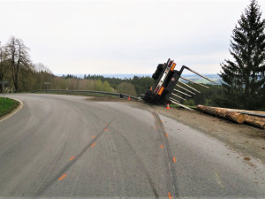 Kamion s nákladem dřeva nezvládl průjezd zatáčkou, položil se na bok a zřítil ze svahu