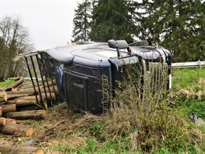 Kamion s nákladem dřeva nezvládl průjezd zatáčkou, položil se na bok a zřítil ze svahu