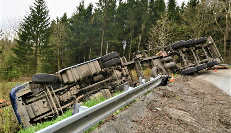 Kamion s nákladem dřeva nezvládl průjezd zatáčkou, položil se na bok a zřítil ze svahu