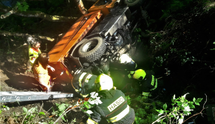 Hasiči se záchranáři se snaží vyprostit řidiče zaklíněného pod vozidlem