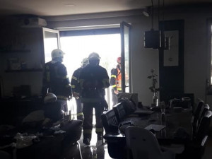 Obyvatelé bytového domu opustili kvůli požáru své domovy, jeden hasič při zásahu zkolaboval