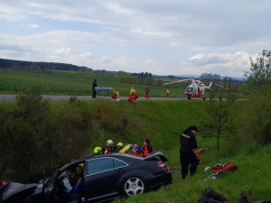 Při hrozivém čelním střetu luxusního mercedesu s nákladním vozidlem pro přepravu dřeva se těžce zranili dva lidé