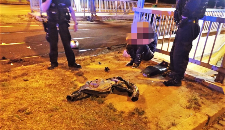 Strážníci hlídají motorkáře, který havaroval se svým strojem. Kolem leží trosky jeho motorky
