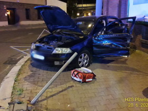 Trolejbus po střetu odmrštil osobní automobil přes chodník a zábradlí až na zeď s billboardem. Dva lidé se zranili