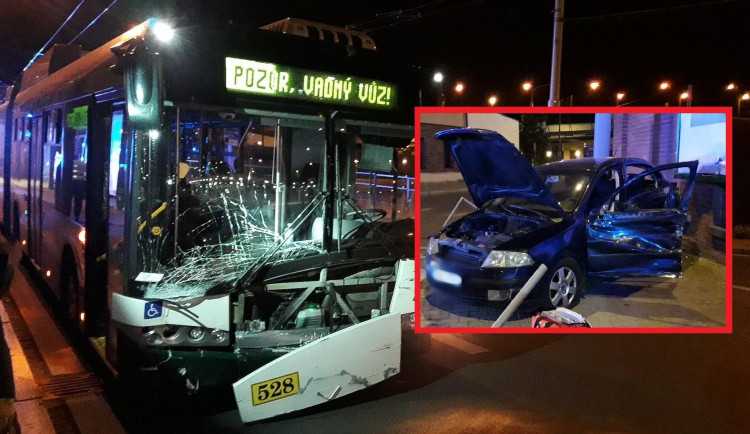 Trolejbus po střetu odmrštil osobní automobil přes chodník a zábradlí až na zeď s billboardem. Dva lidé se zranili