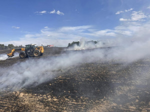 V příšerném vedru bojují hasiči s obrovským požárem pole a lesa na ploše 25 hektarů. Hořet začalo od balíkovače