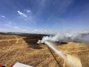 V příšerném vedru bojují hasiči s obrovským požárem pole a lesa na ploše 25 hektarů. Hořet začalo od balíkovače