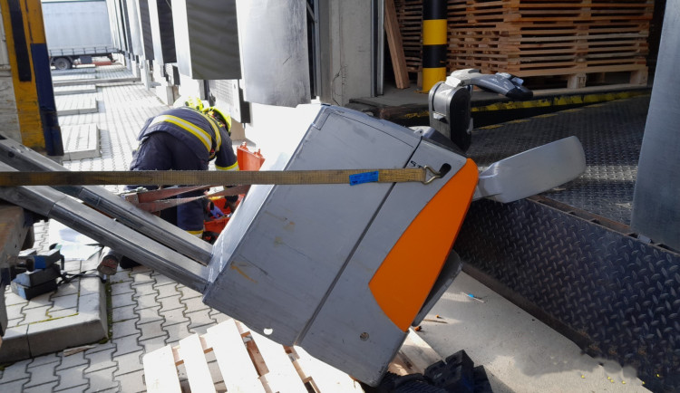 Elektrický paletový vozík přimáčkl k nakládací rampě pracovníka firmy. Zraněného muže vyprošťovali hasiči