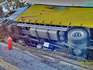 Z kabiny kamionu převráceného na bok vyprošťovali hasiči zraněného řidiče na páteřové desce