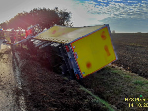 Z kabiny kamionu převráceného na bok vyprošťovali hasiči zraněného řidiče na páteřové desce