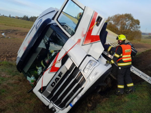 Z kabiny kamionu převráceného na bok vyprošťovali hasiči zraněného řidiče na páteřové desce