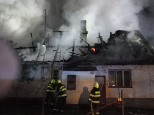 Hasiči bojují s požárem rodinného domu, snaží se uchránit před plameny sousední penzion