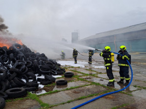 Hasiči bojují s rozsáhlým požárem pneumatik, k nebi stoupá černý dým