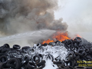 Hasiči bojují s rozsáhlým požárem pneumatik, k nebi stoupá černý dým