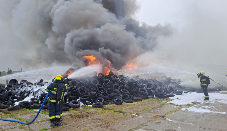 Hasiči bojují s rozsáhlým požárem pneumatik, k nebi stoupá černý dým