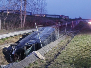 Mikrobus po střetu s osobákem vyletěl z dálnice, prorazil oplocení a skončil na boku