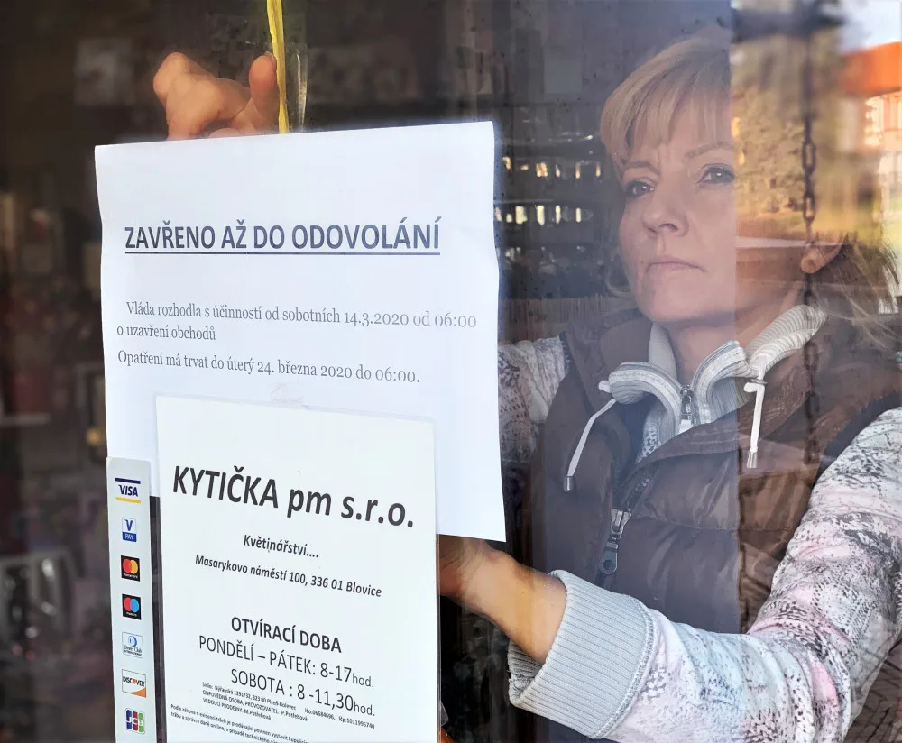 Majitelka květinářství Petra Potřebová vylepuje na dveře provozovny ceduli informující o uzavření obchodu na základě vládního nařízení