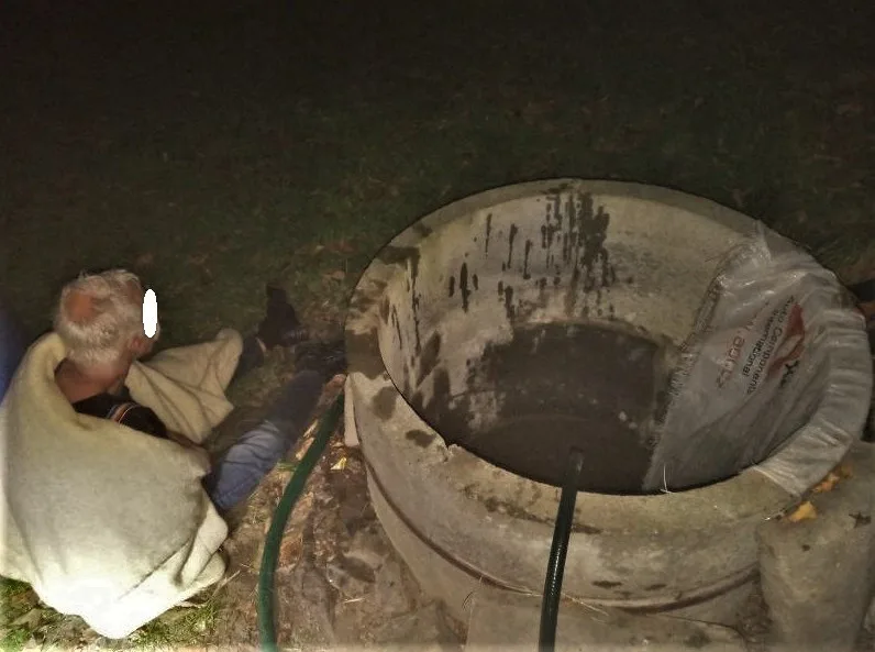 Zachráněný muž vedle studny, která se mohla stát jeho hrobem