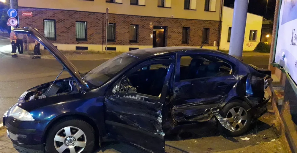 Trolejbus po střetu odmrštil osobní automobil přes chodník a zábradlí až na zeď s billboardem. Dva lidé se zranili
