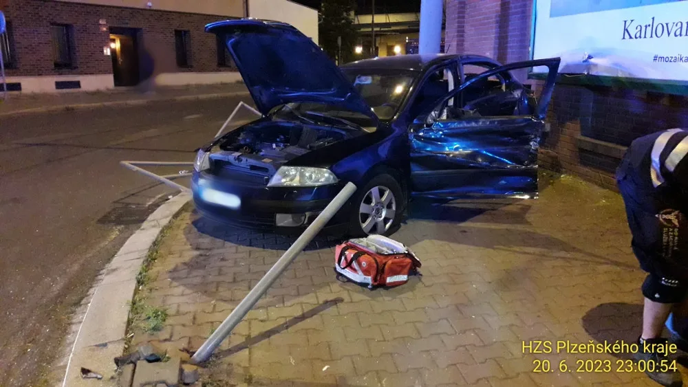 Trolejbus po střetu odmrštil osobní automobil přes chodník a zábradlí až na zeď s billboardem. Dva lidé se zranili