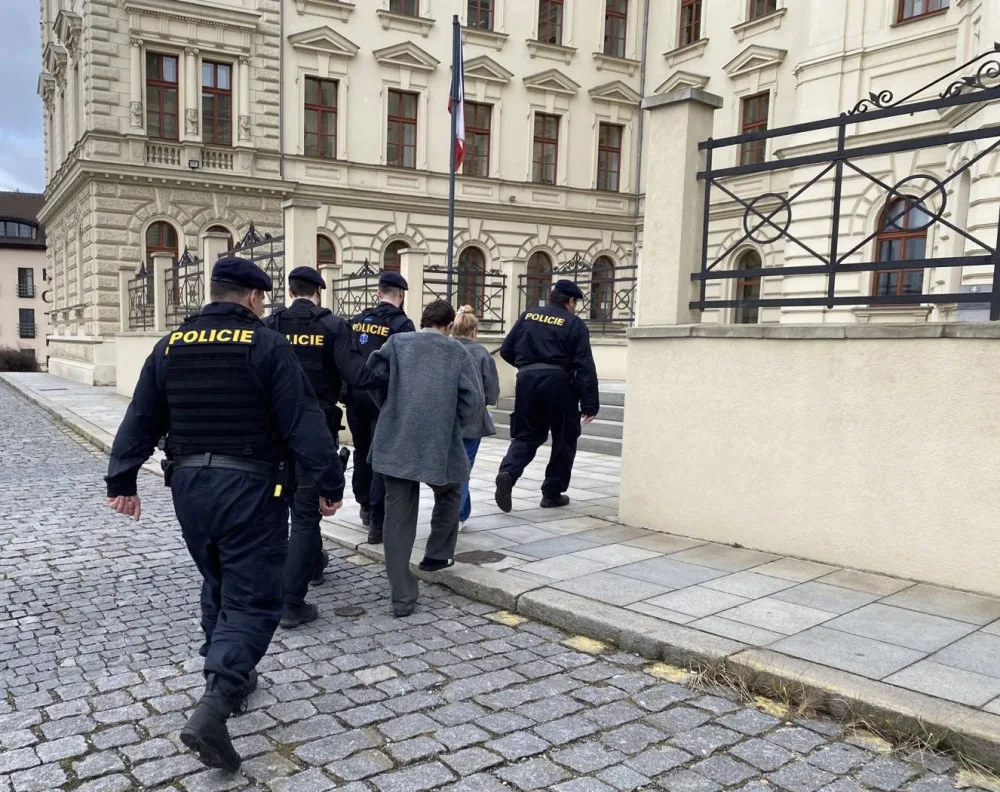 Policisté vedou obviněné cizince do budovy městského soudu, který následně rozhodl o jejich umístění do vazby