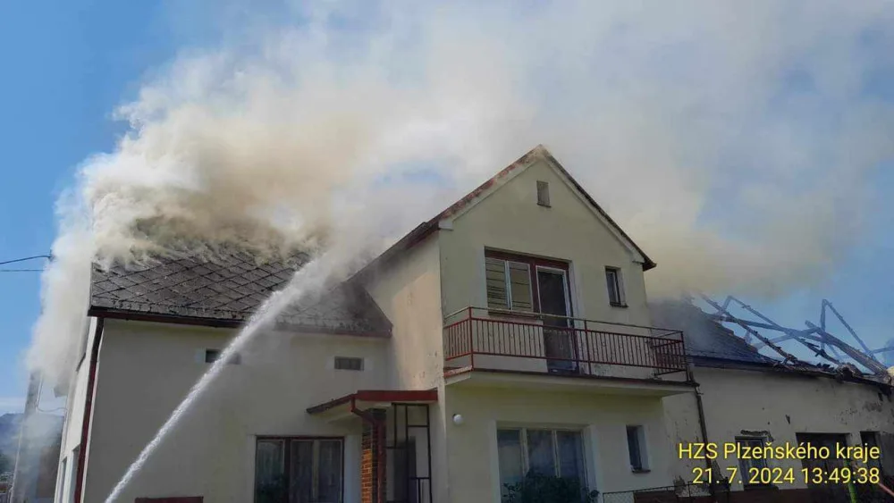 Na Domažlicku hoří hromada pneumatik a okolní budovy, ve vedru kolabují hasiči