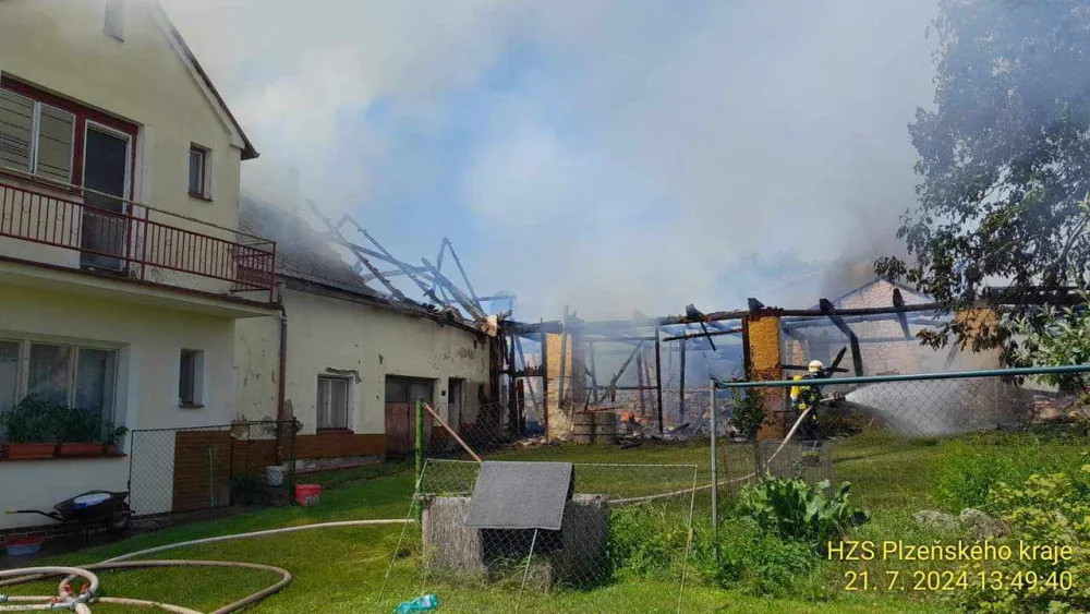 Na Domažlicku hoří hromada pneumatik a okolní budovy, ve vedru kolabují hasiči