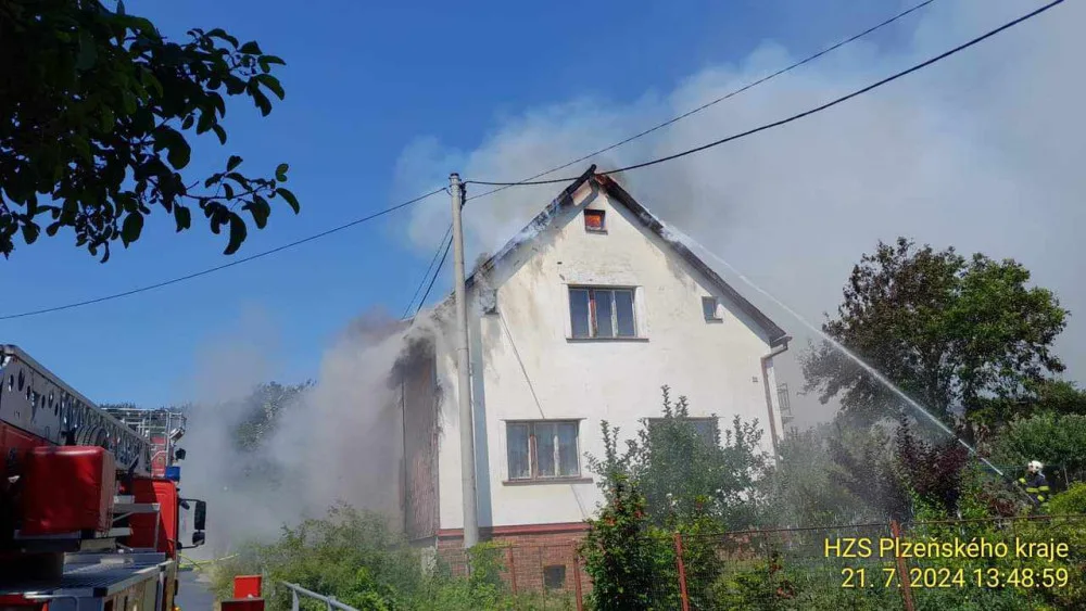 Na Domažlicku hoří hromada pneumatik a okolní budovy, ve vedru kolabují hasiči