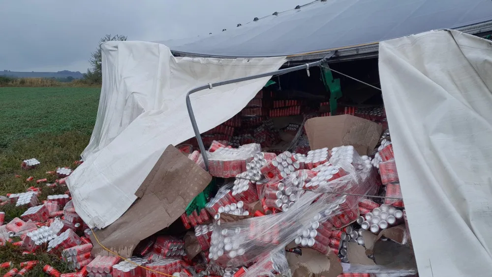 Na pole se vysypaly stovky plechovek Coca-Coly z převráceného kamionu