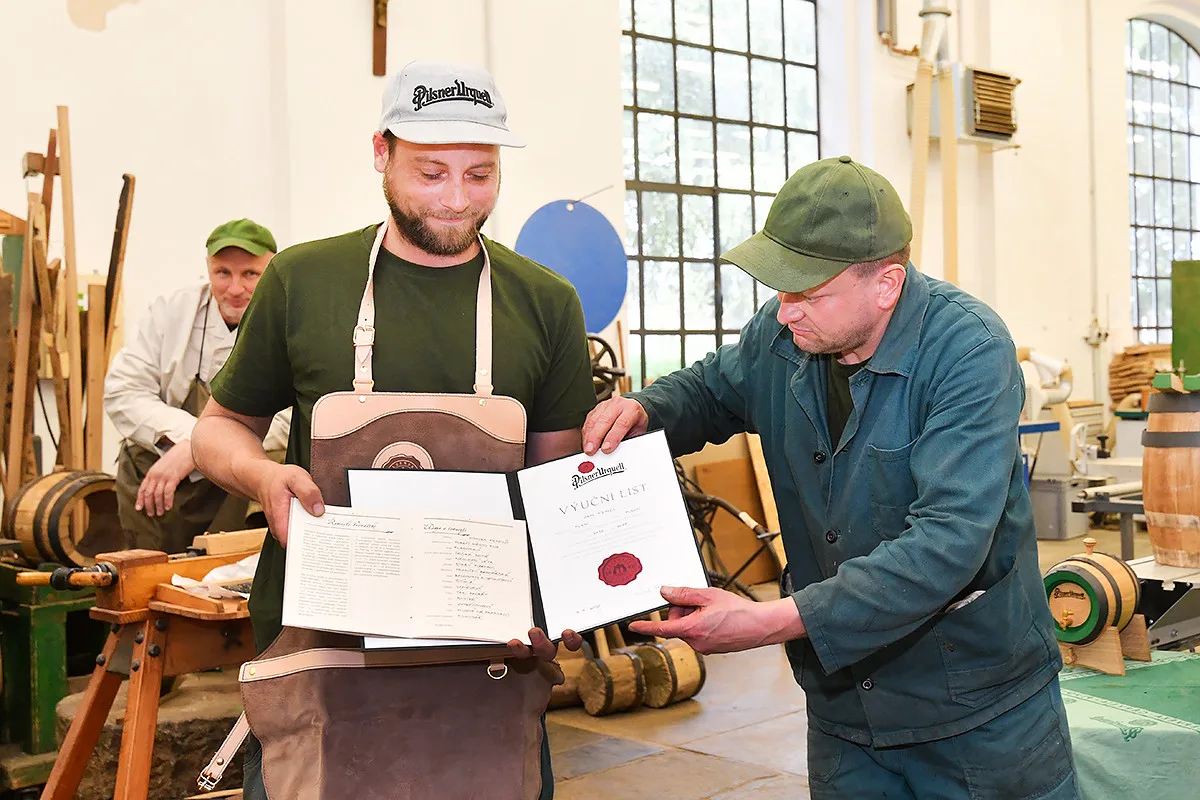Slavní bednáři v Prazdroji pasovali nového člena. Společně smolili obří pivní sudy