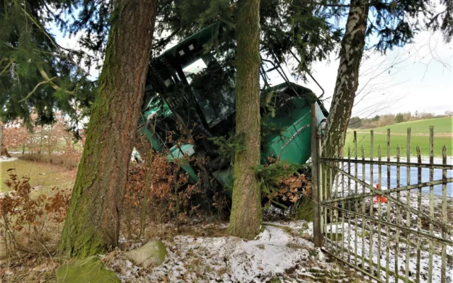 Po smyku na kluzké vozovce ukončil těžký stavební stroj svoji jízdu nárazem do stromů