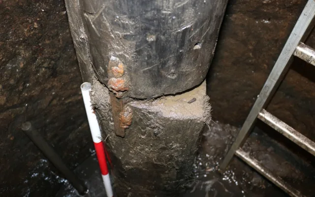 Napojení spodní části historického potrubí na dřevěnou trámovou podstavu v 15 metrech hloubky studny. Archeologickým odkryvem byly zachyceny prvky původních spojů.