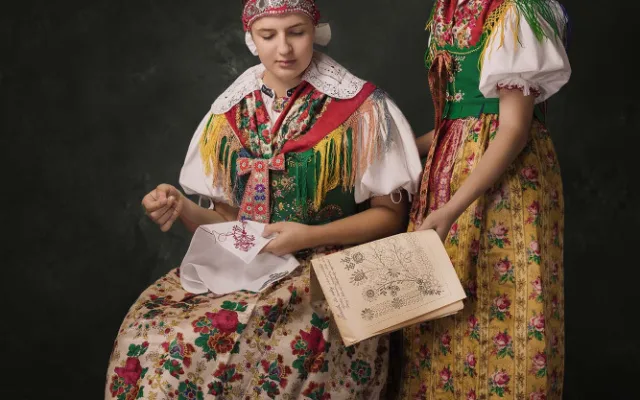Co s dlouhými podzimními večery? Ideální příležitost věnovat se ruční práci! Dívky z Postřekova na sobě mají tradiční atlasové fěrtochy s kvítky, které byly součástí slavnostního, takzvaného velkého kroje. Hlavy jim zdobí vínky, pozůstatek starých slavnos