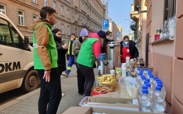 Dobrovolníci z centra Totem nabízí lidem teplý čaj, ovoce nebo sladkosti pro děti.