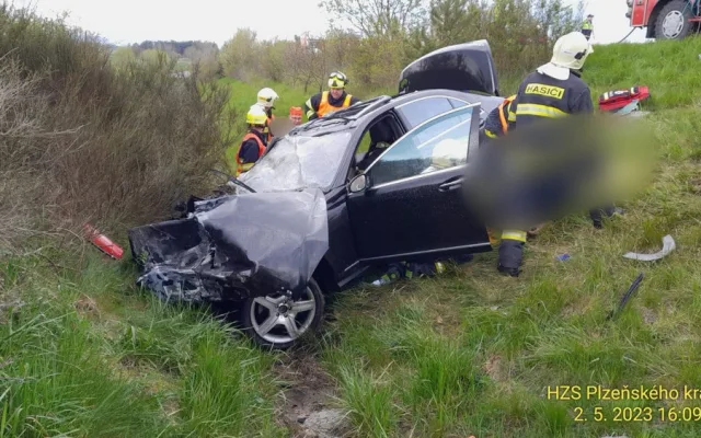 Při hrozivém čelním střetu luxusního mercedesu s nákladním vozidlem pro přepravu dřeva se těžce zranili dva lidé