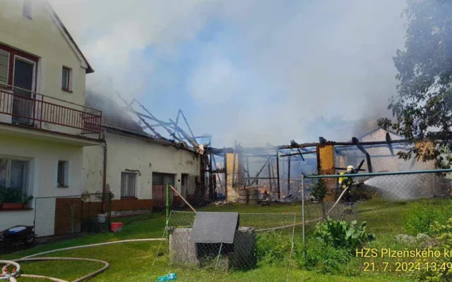 Na Domažlicku hoří hromada pneumatik a okolní budovy, ve vedru kolabují hasiči