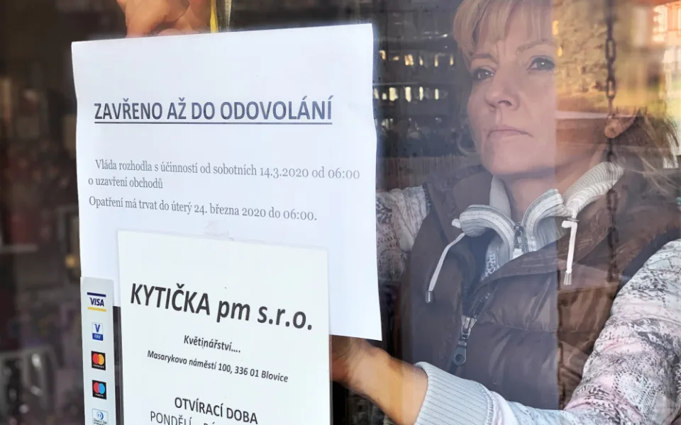 Majitelka květinářství Petra Potřebová vylepuje na dveře provozovny ceduli informující o uzavření obchodu na základě vládního nařízení