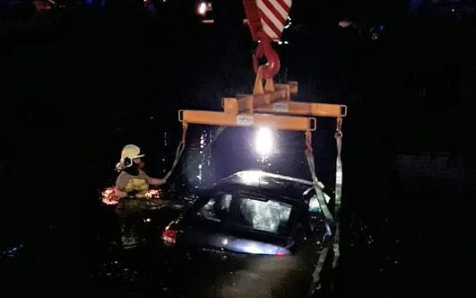 Hasiči vyprošťují auto ze dna rybníka pomocí jeřábu