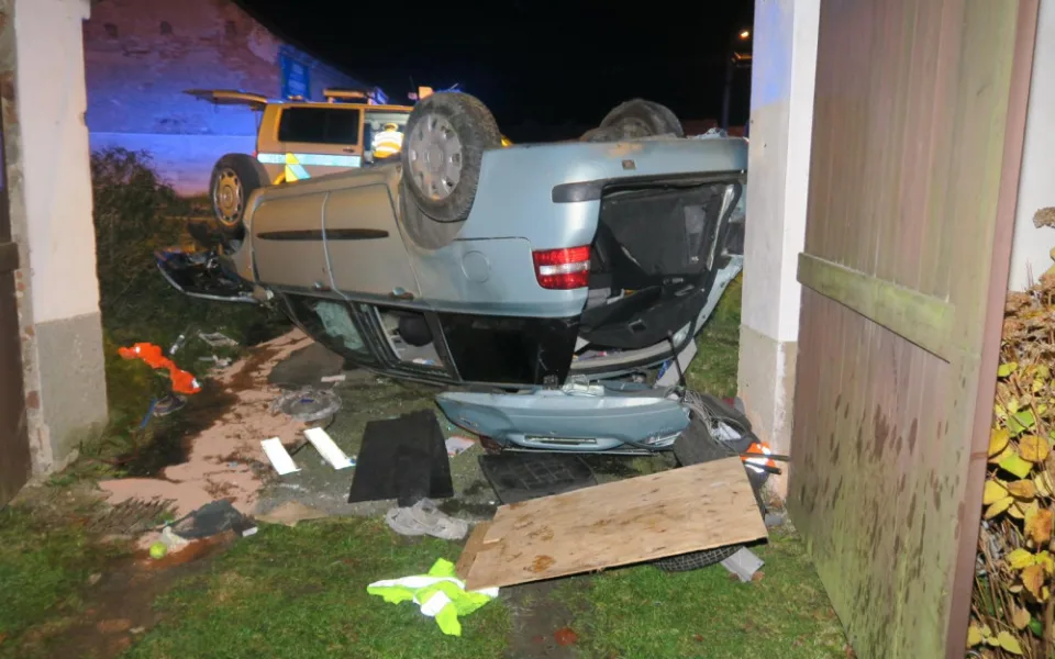 Auto zbořilo hradbu a přistálo na střeše ve vjezdu dalšího domu, řidič od nehody ujel jiným vozem